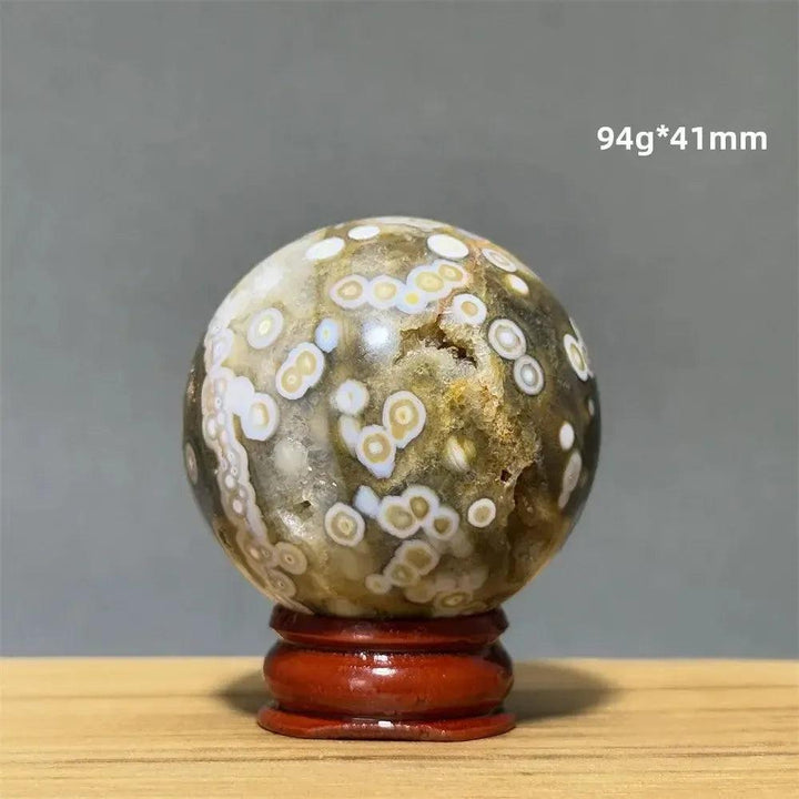 Ocean Jasper sphere from Crystal Destiny, 94g*41mm, with green, white, cream, pink, and red orbicular patterns on a wooden base.