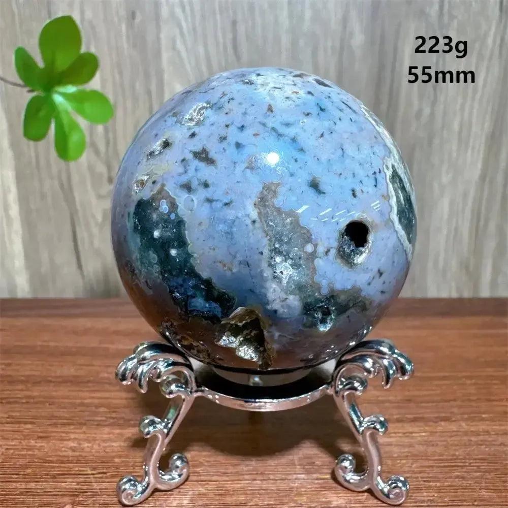 Ocean Jasper sphere from Crystal Destiny, featuring unique blue, green, and white orbicular patterns on a silver stand.