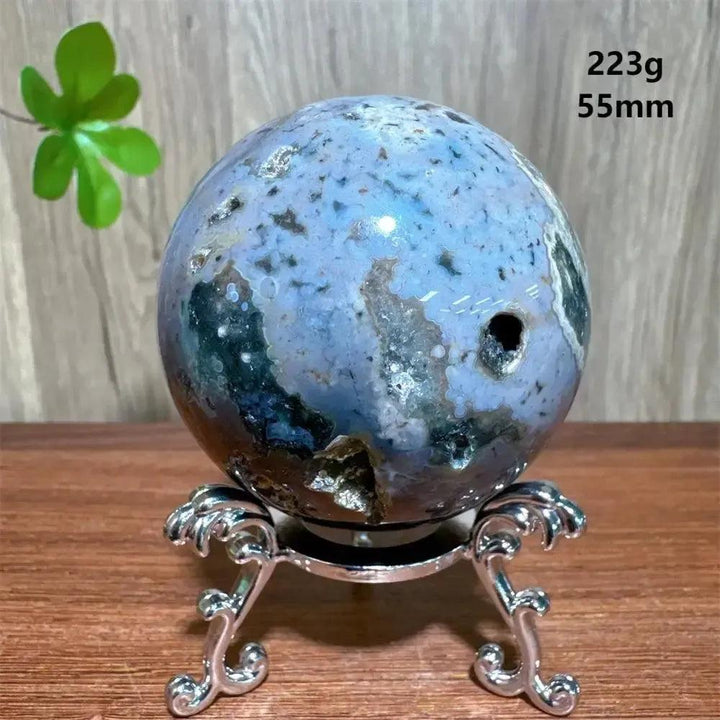 Ocean Jasper sphere from Crystal Destiny, featuring unique blue, green, and white orbicular patterns on a silver stand.