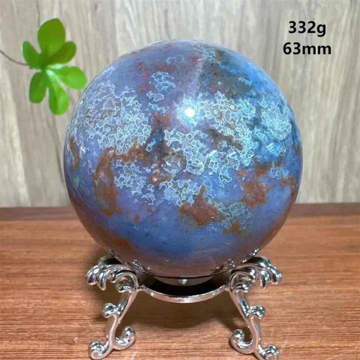 Ocean Jasper sphere from Crystal Destiny, featuring blue, purple, and brown orbicular patterns on a silver stand.