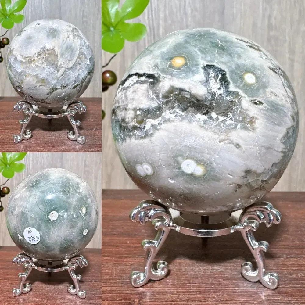 Ocean Jasper sphere from Crystal Destiny, featuring unique green, white, and brown orbicular patterns on a silver stand.