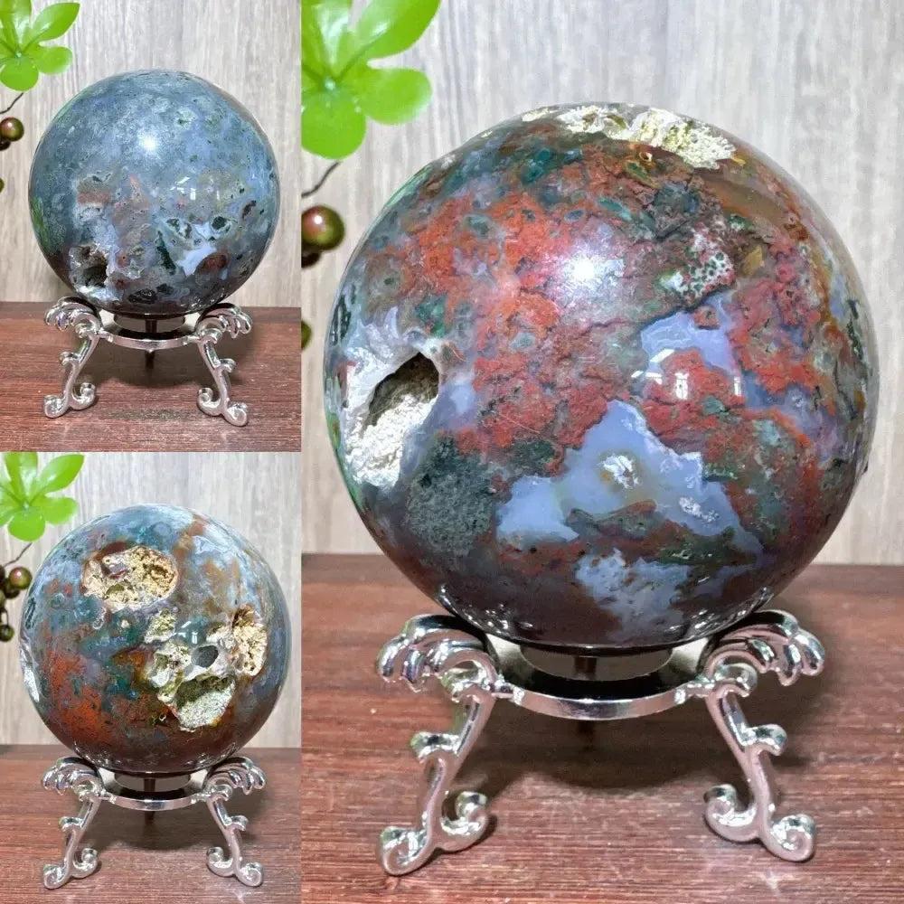 Ocean Jasper sphere from Crystal Destiny, displaying unique orbicular patterns in greens, reds, whites, and blues on a stand.