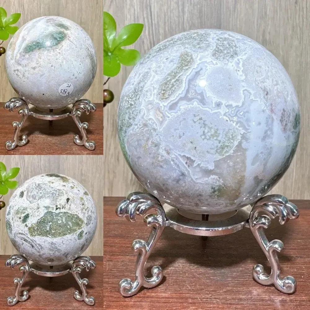 Ocean Jasper sphere from Crystal Destiny, displaying unique green, white, and pink orbicular patterns on a silver stand.