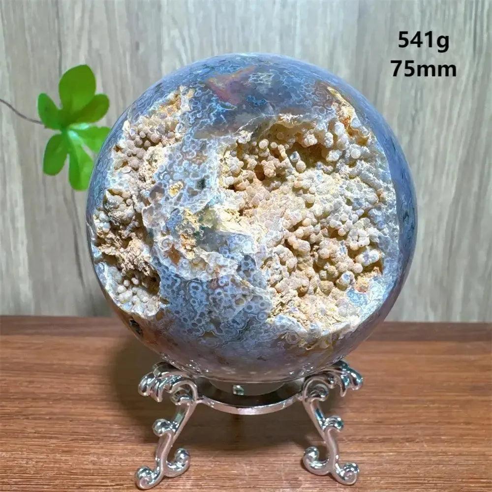 Ocean Jasper sphere with a large druzy cave, displaying unique orbicular patterns and earthy tones on a silver stand.