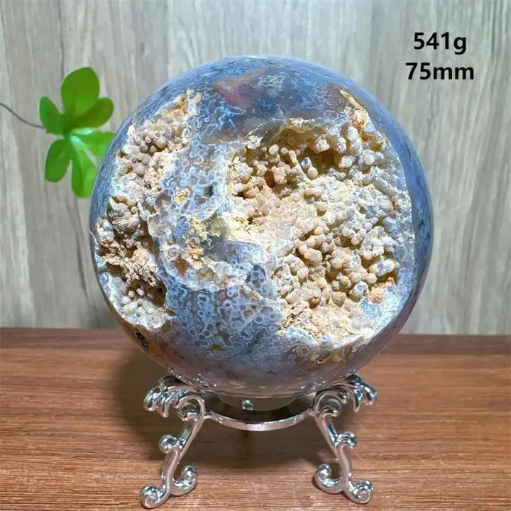 Ocean Jasper sphere with a large druzy cave, displaying unique orbicular patterns and earthy tones on a silver stand.