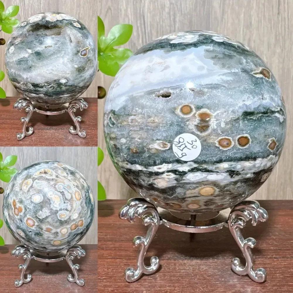Ocean Jasper sphere from Crystal Destiny, featuring unique green, white, and brown orbicular patterns on a silver stand.