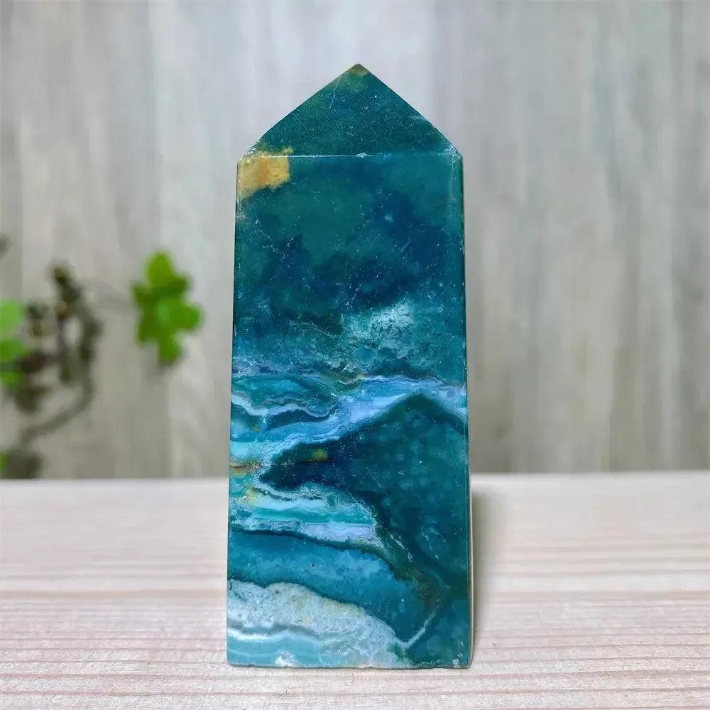 Polished blue and green Ocean Jasper tower with swirling patterns and natural druzy inclusions, supporting Heart and Throat Chakras.