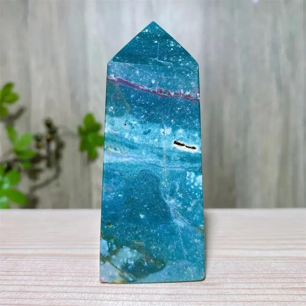 Polished blue Ocean Jasper tower with swirling patterns, red veins, and a small druzy inclusion, supporting Heart and Throat Chakras.