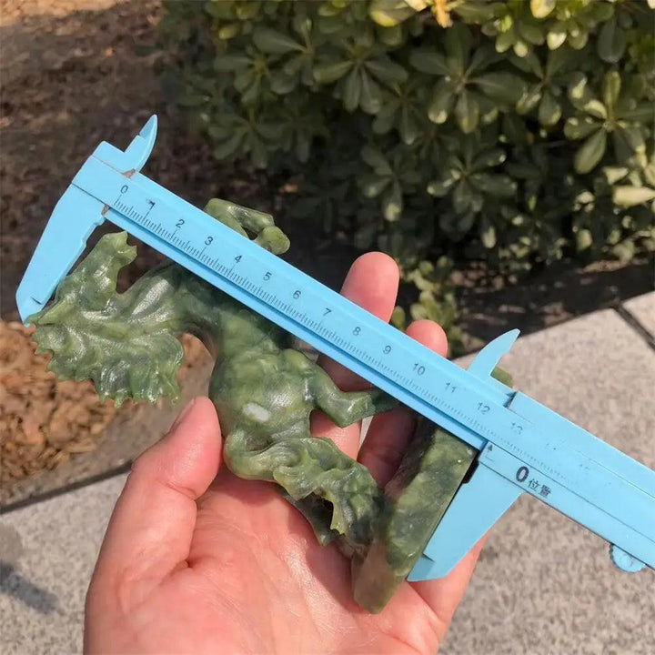 Hand-carved Ophiolite horse sculpture in deep green, showing grounding energy and polished crystal detail with a caliper.