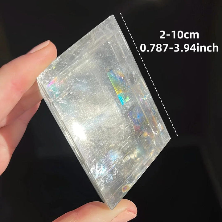 Clear Brazilian optical calcite cube with iridescent flashes, held in hand, showing 2-10cm size.