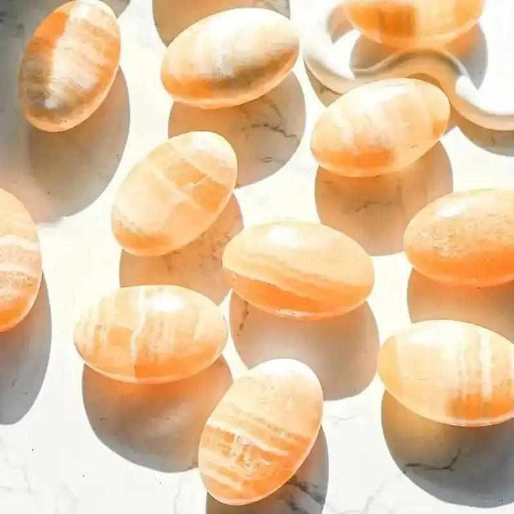 Smooth, glowing orange calcite palm stones with polished surfaces, perfect for sacral chakra energy and creative focus.