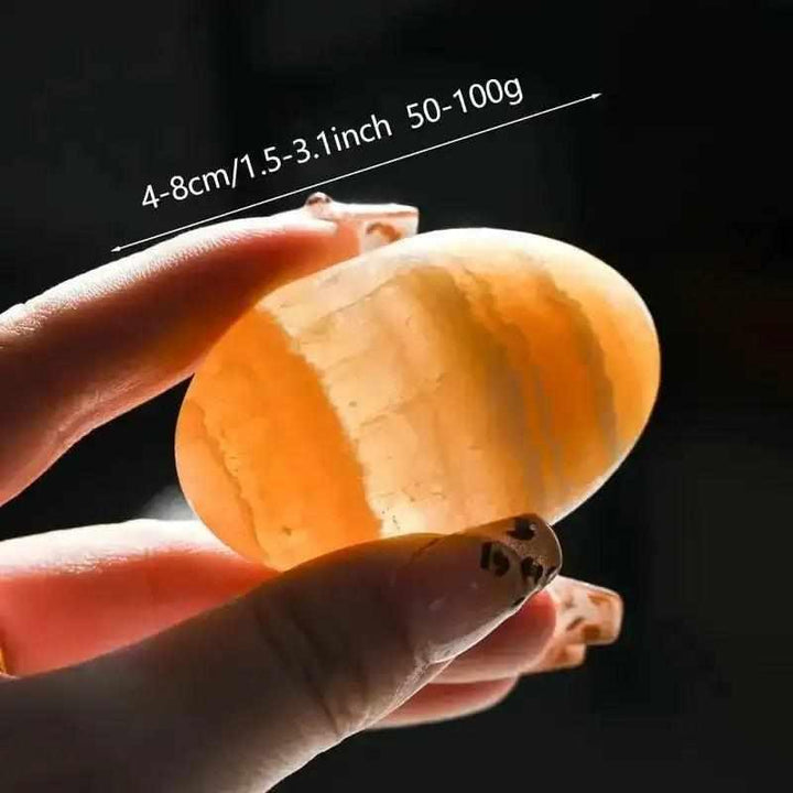 Smooth, glowing orange calcite palm stone held in hand, perfect for sacral chakra energy and creative inspiration.