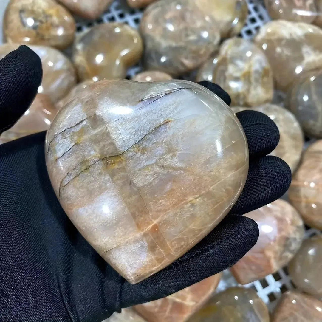 Hand-carved Orange Moonstone heart from Crystal Destiny, glowing with peachy-orange tones and iridescent shimmer.