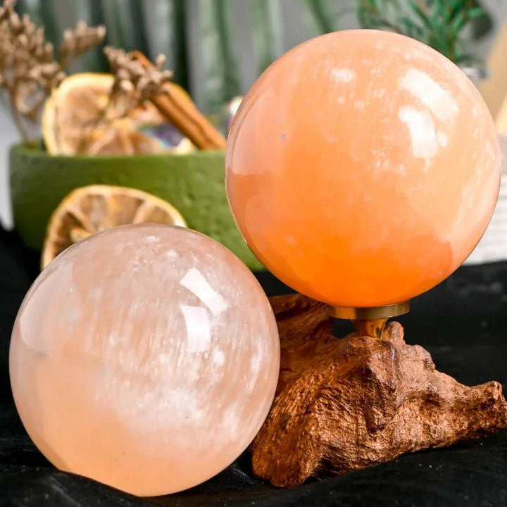 Polished Orange Selenite crystal spheres with warm, translucent peach tones for healing and radiant energy.