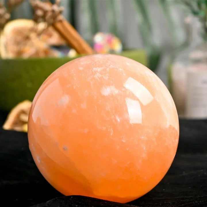 Polished orange selenite crystal sphere with a warm, translucent peach glow for healing and peaceful energy.