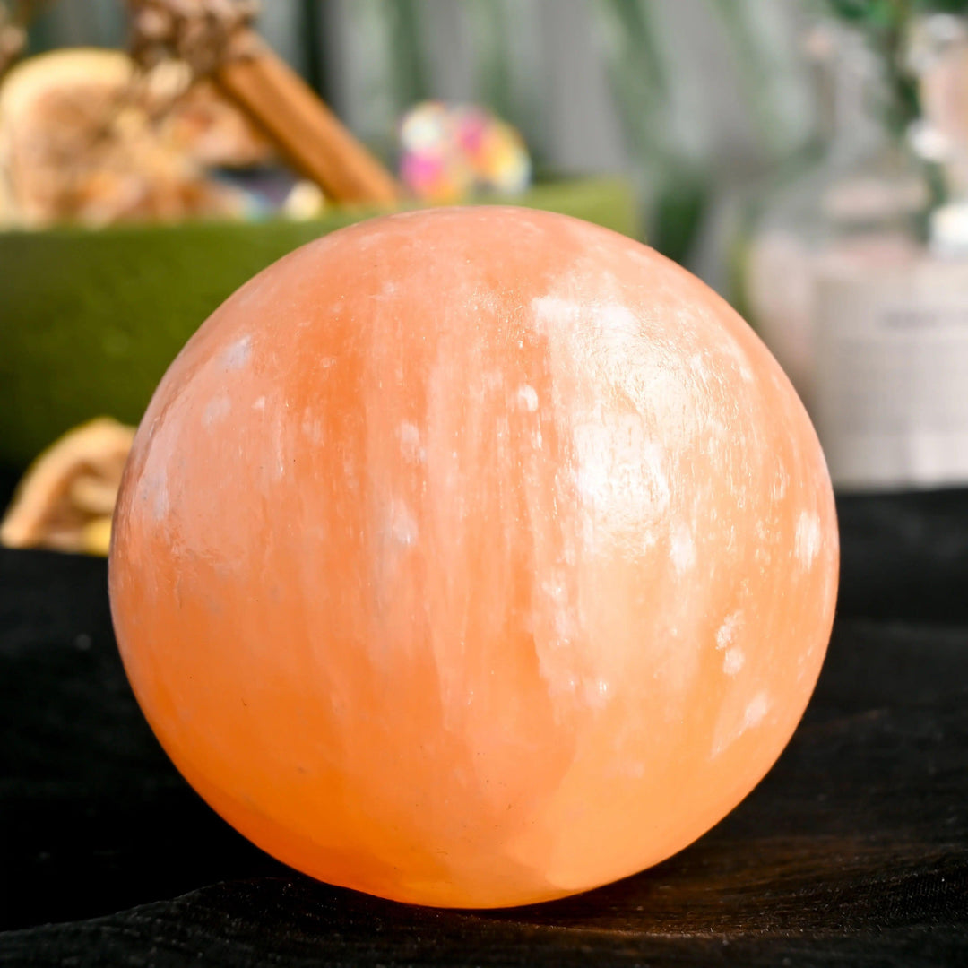 Polished orange selenite crystal sphere with a warm, translucent peach glow for healing and tranquil energy.