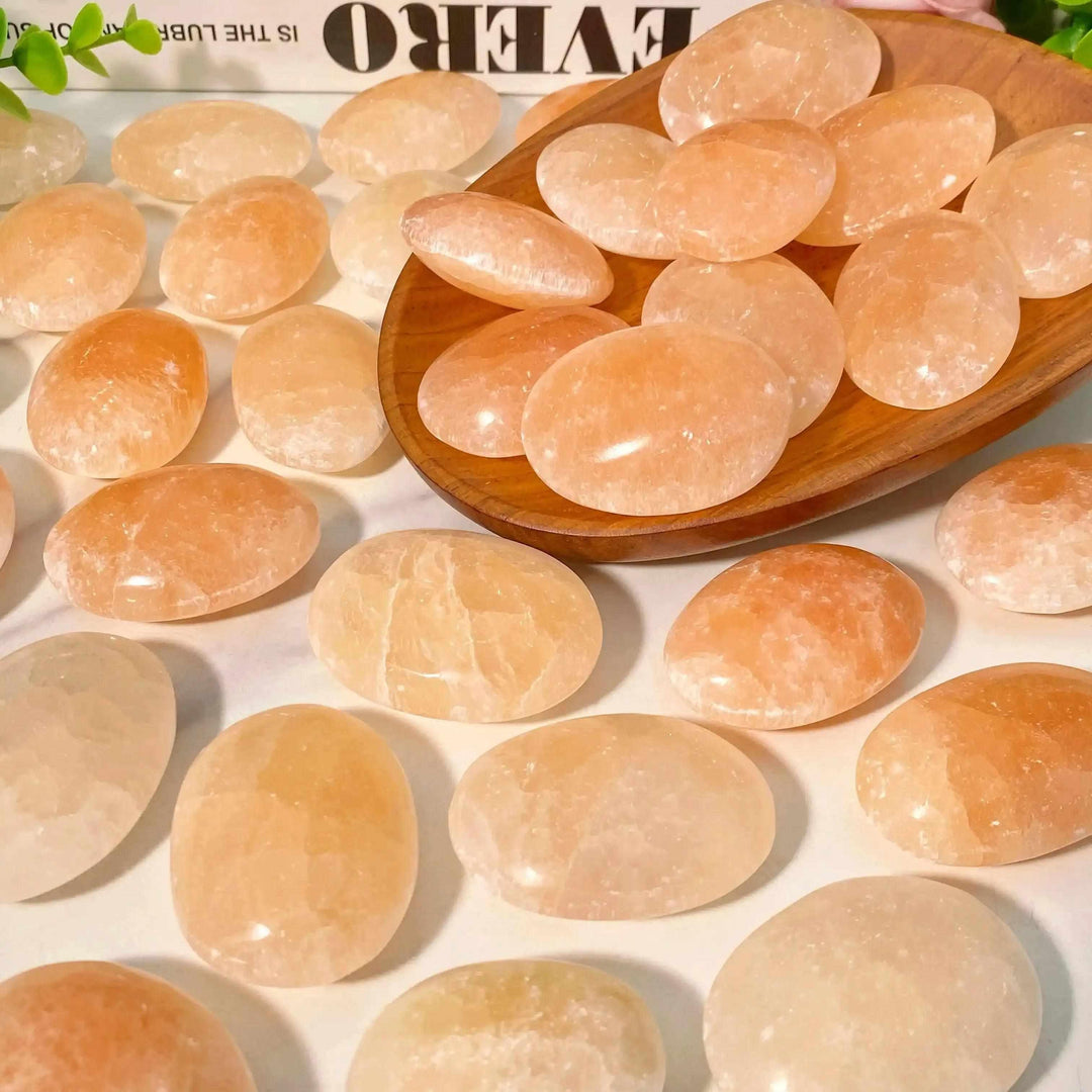 Smooth, polished Orange Selenite palm stones in warm peach tones with a silky, glowing finish, perfect for chakra healing.