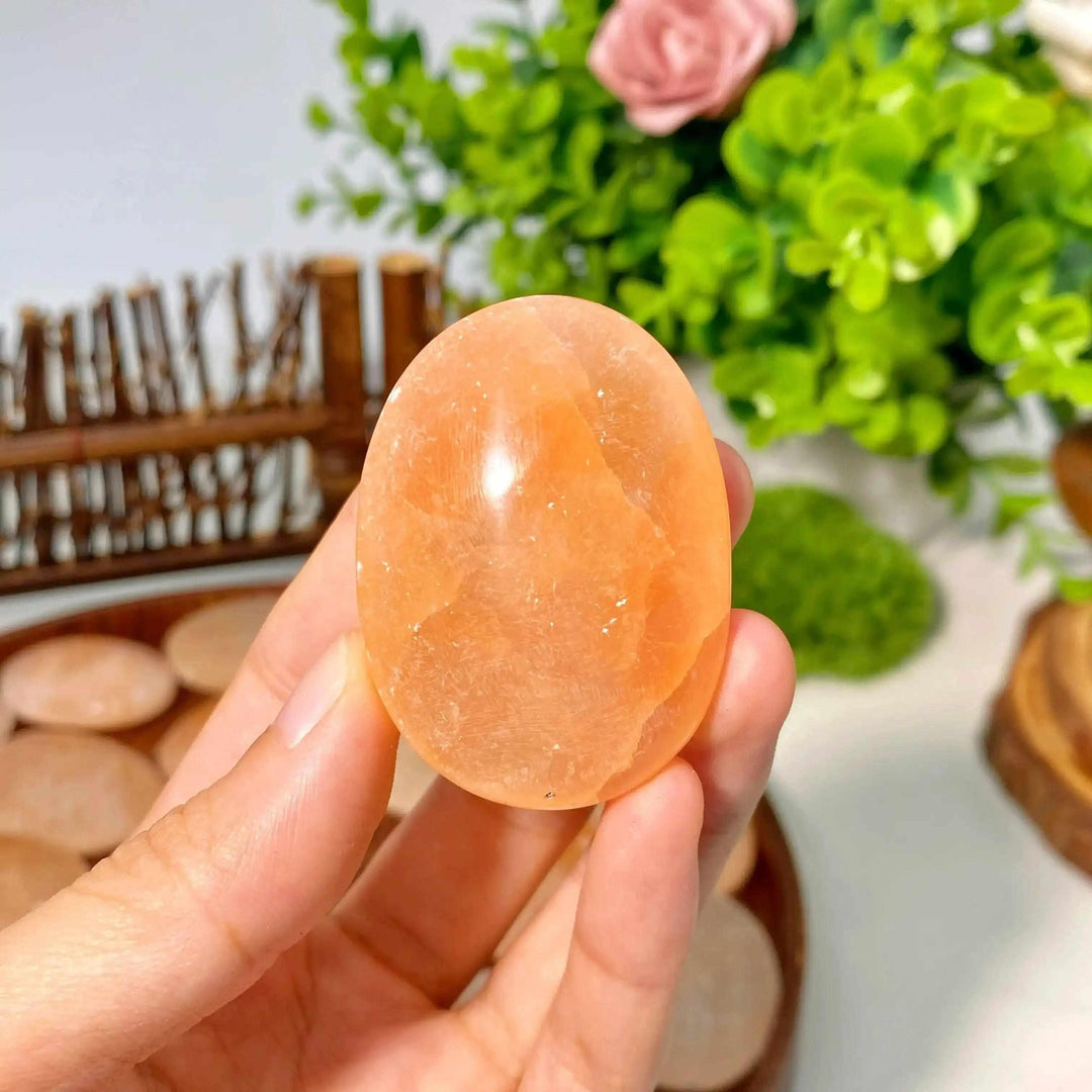 Smooth, polished Orange Selenite palm stone with a silky, glowing peach finish, perfect for Sacral Chakra meditation.