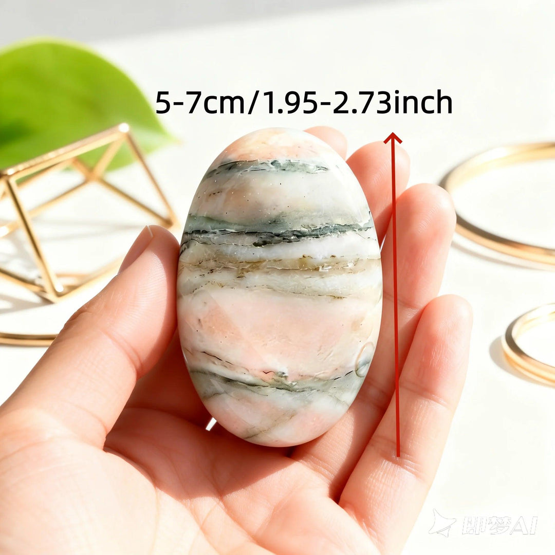 Polished orange sunstone palm stone with natural green stripes, held in hand to show its 5-7cm size.