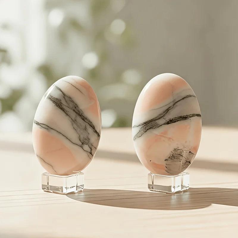 Two polished orange sunstone crystal palm stones with black veins on clear stands.