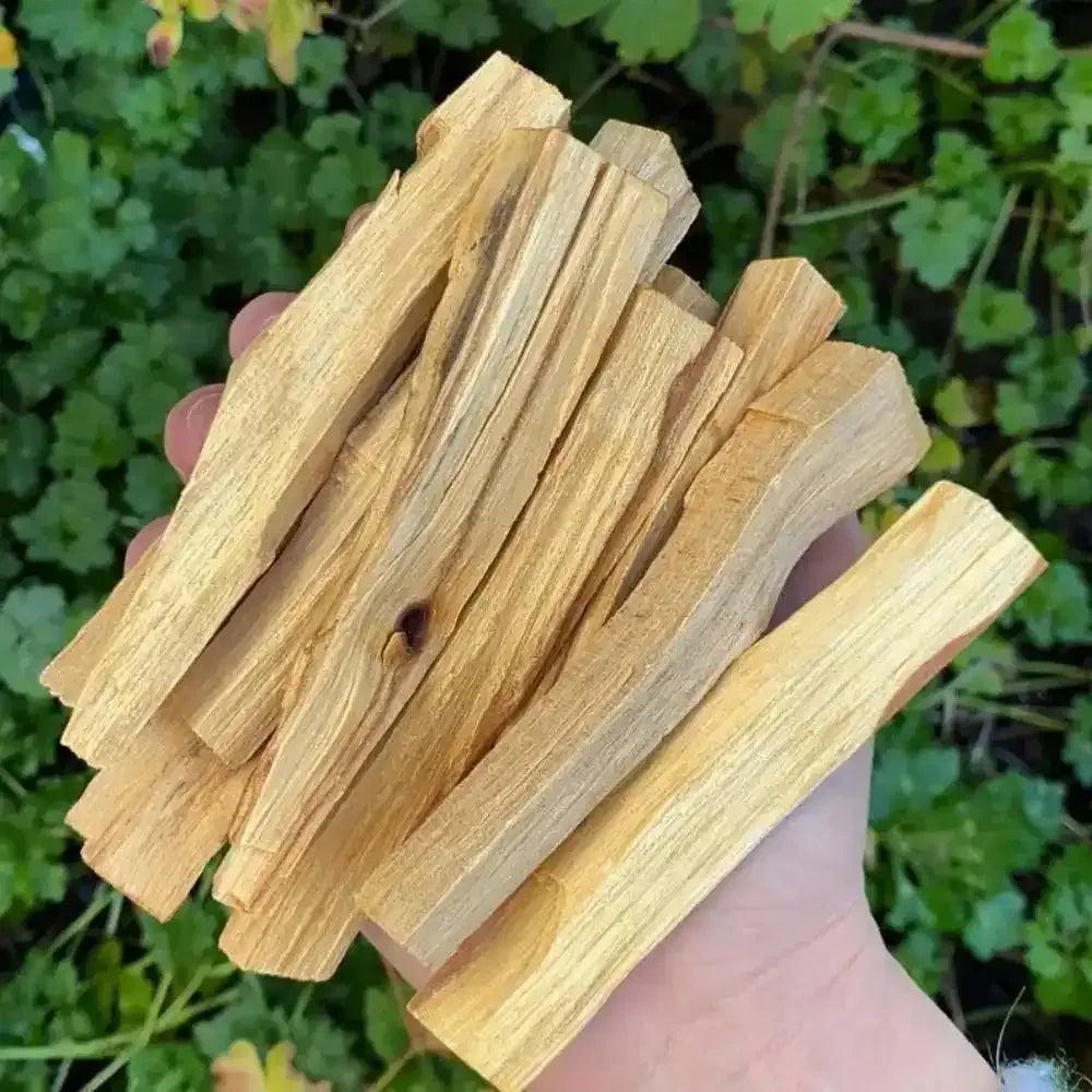 Handheld bundle of golden Palo Santo wood sticks with natural grain and knots for cleansing and intention rituals.