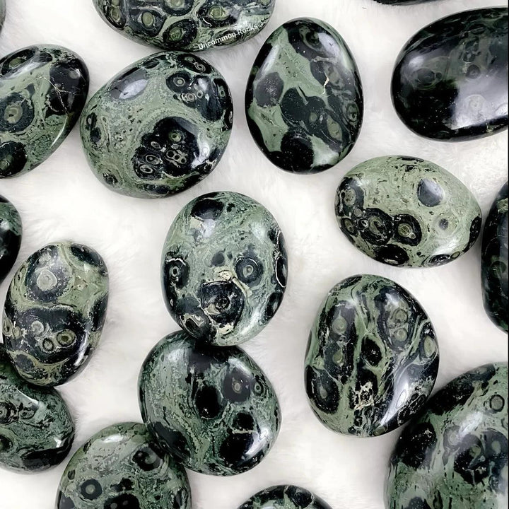 Polished green and black Peacock Eye Crystal Palm Stones for grounding, protection, and third eye chakra healing.