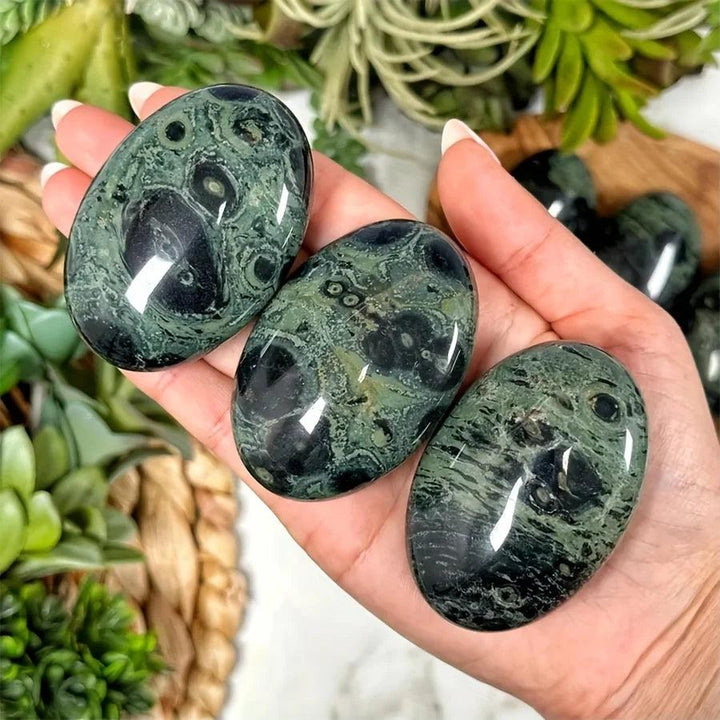 Polished green and black Peacock Eye Crystal Palm Stones for grounding and protection.