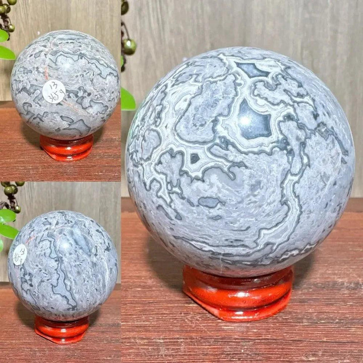 Polished Picasso Jasper Sphere with abstract gray, black, brown, and cream patterns on a red stand.