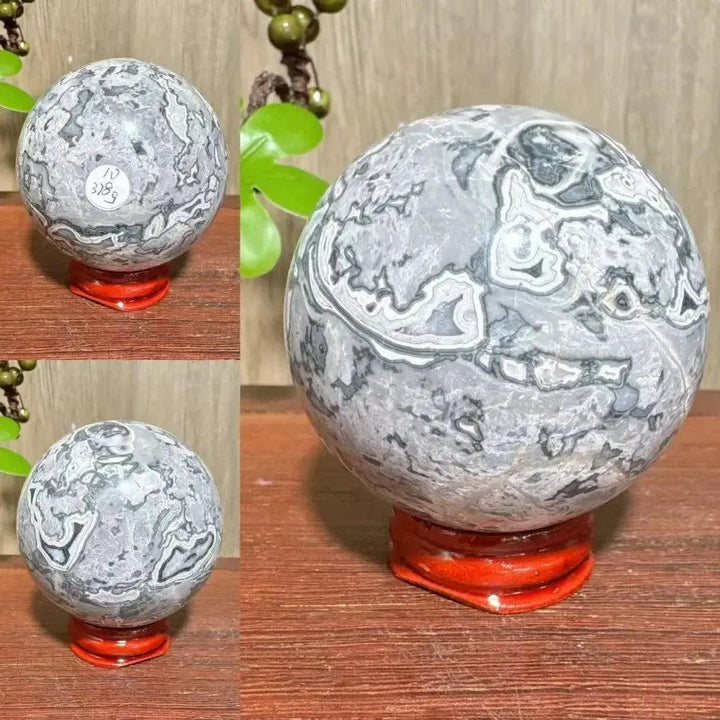 Polished Picasso Jasper Sphere with abstract gray, black, brown, and cream patterns, on a red stand.