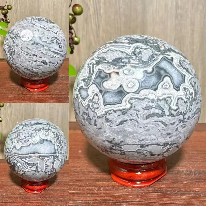 Polished Picasso Jasper Sphere with abstract gray, black, brown, and cream patterns on a red stand.
