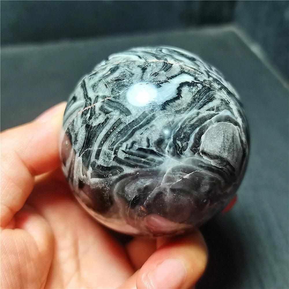 Polished Picasso Jasper sphere featuring abstract black, gray, and cream lines for grounded creativity and meditation.