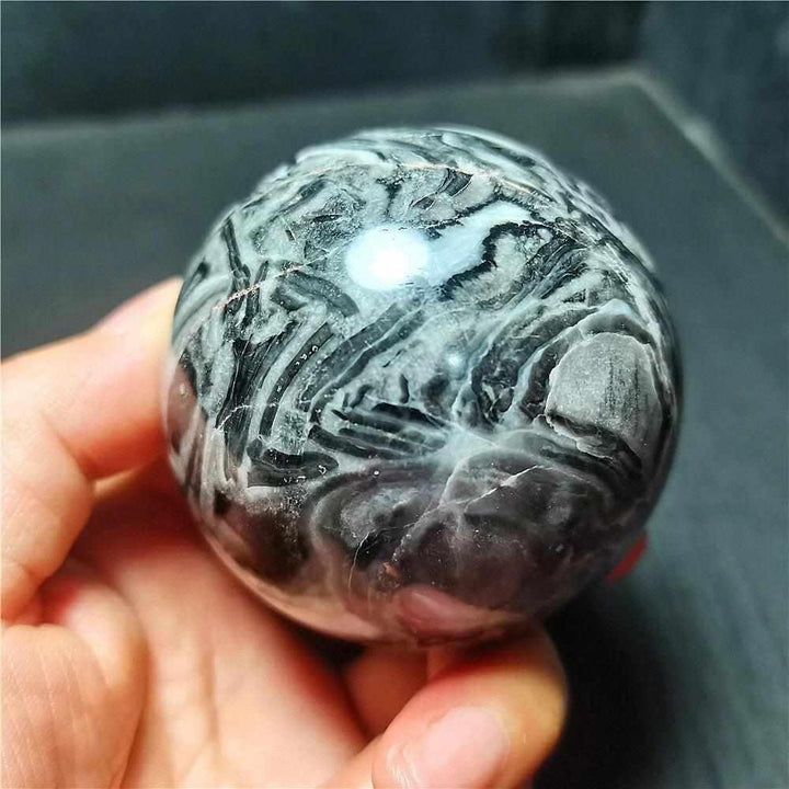 Polished Picasso Jasper sphere featuring abstract black, gray, and cream lines for grounded creativity and meditation.