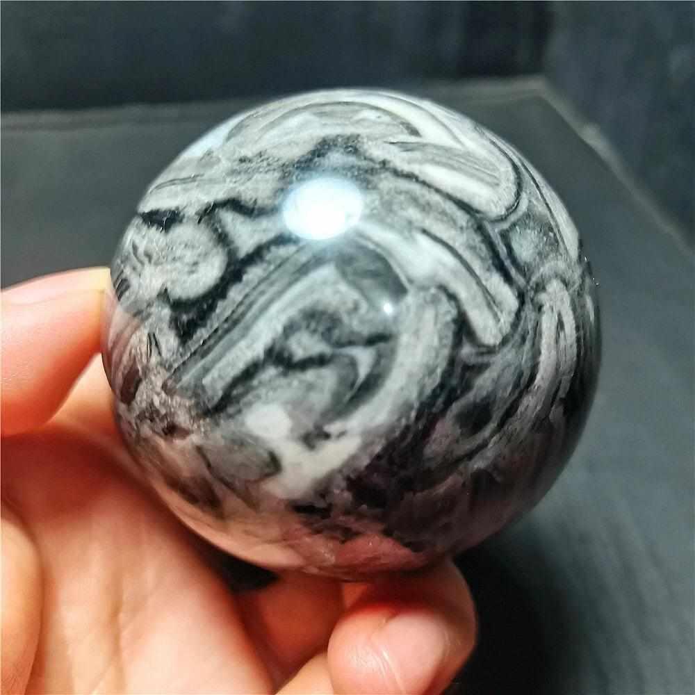 Polished Picasso Jasper sphere featuring abstract black, gray, and cream lines for grounded creativity and meditation.