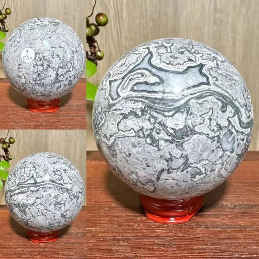 Picasso Jasper sphere from Crystal Destiny, featuring abstract gray, black, and white patterns on a red stand.