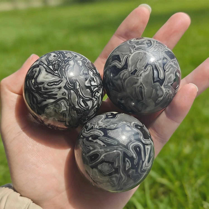 Polished Picasso Jasper spheres featuring abstract black, gray, and cream lines for grounded creativity and chakra balance.