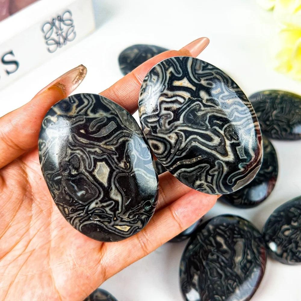 Natural Dragon Patterned Picasso stone palm ornament with unique black and white striped crystal textures for healing.