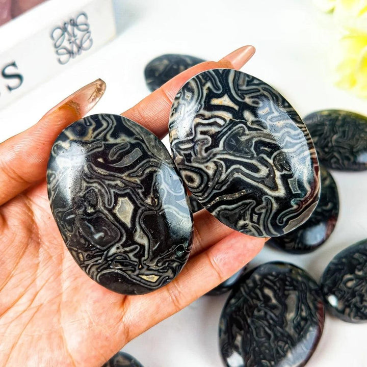 Natural Dragon Patterned Picasso stone palm ornament with unique black and white striped crystal textures for healing.