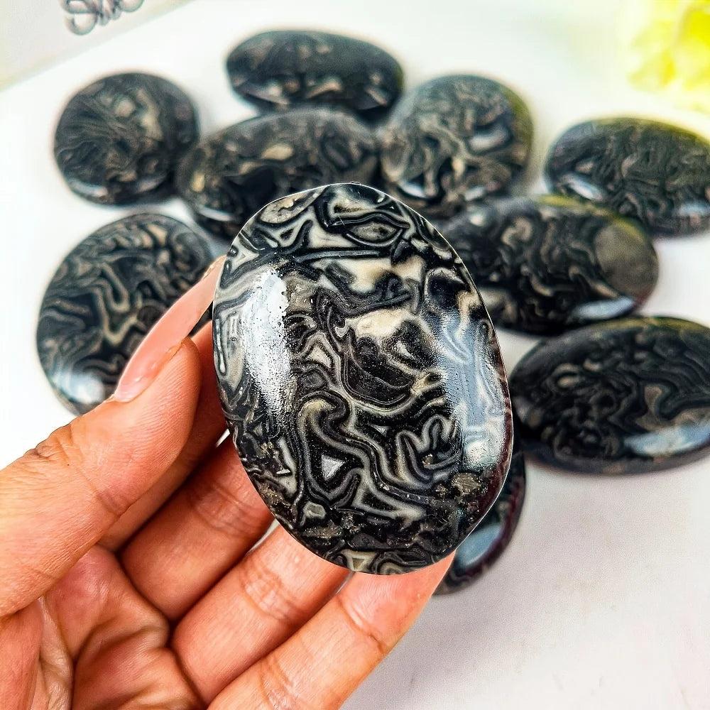 Polished Picasso stone palm ornament featuring unique black and white striped dragon patterns for healing and meditation.