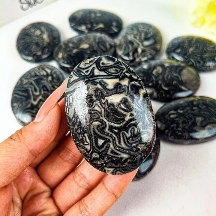 Polished Picasso stone palm ornament featuring unique black and white striped dragon patterns for healing and meditation.