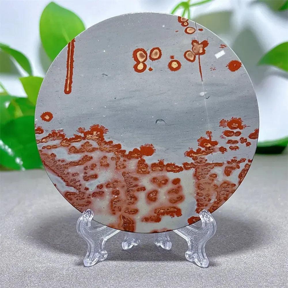 Round Picture Jasper crystal slice with red and brown landscape patterns on a gray background, on a clear stand from Crystal Destiny.