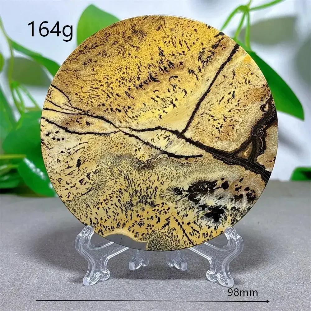 Round Picture Jasper crystal slice with desert landscape patterns in cream, ochre, and deep brown on a clear stand from Crystal Destiny.