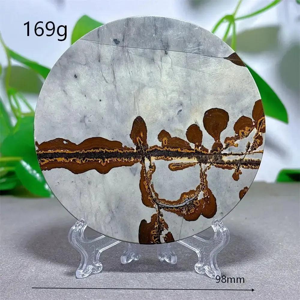 Round Picture Jasper crystal slice with brown landscape patterns on a light gray background, displayed on a clear stand from Crystal Destiny.