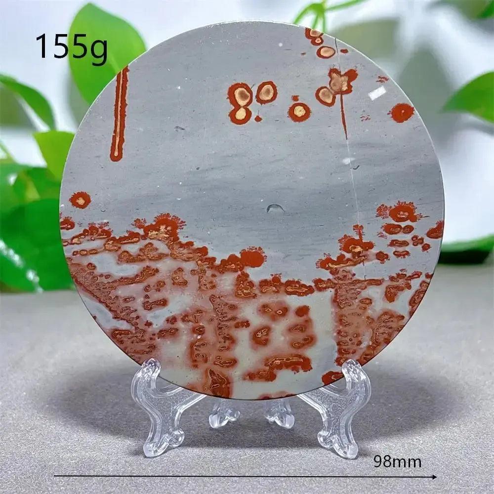 Round Picture Jasper crystal slice with red-brown patterns on a grey background, displayed on a clear stand from Crystal Destiny.