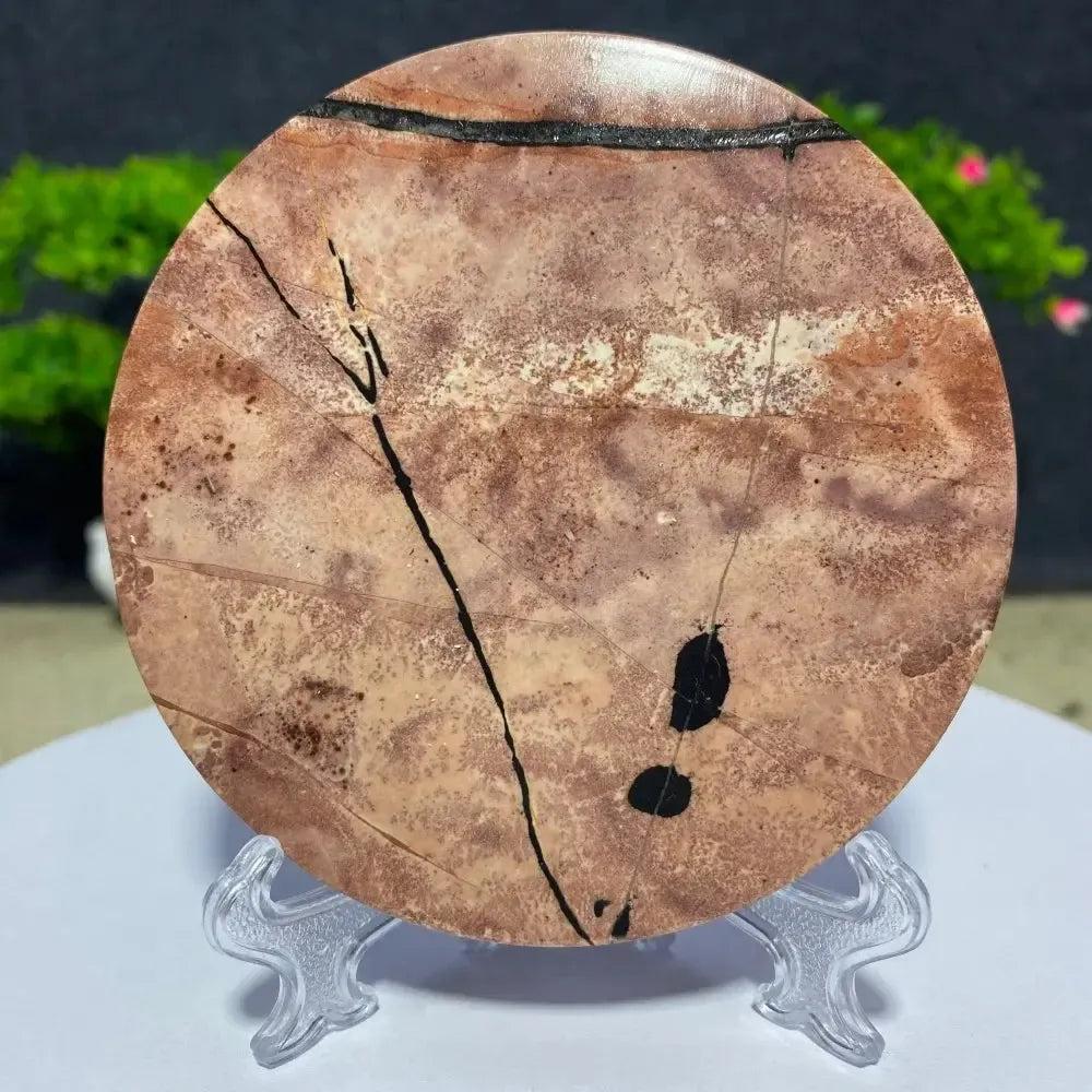Round Picture Jasper slab from Crystal Destiny, featuring natural brown, cream, and black landscape patterns on a clear stand.
