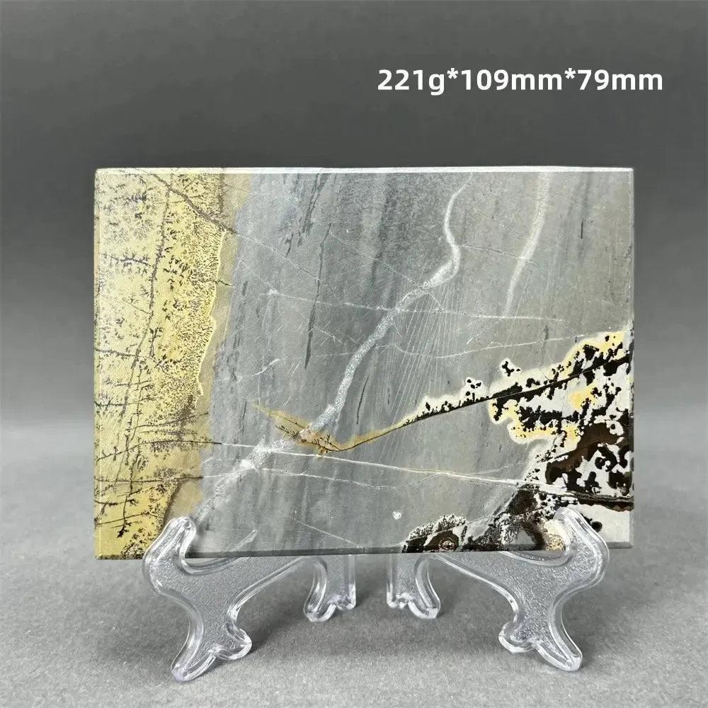 Polished Picture Jasper slice with unique landscape patterns in grey, cream, and brown, displayed on a clear stand.
