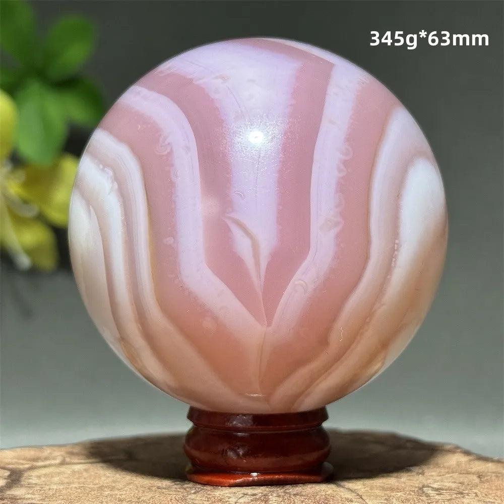 Polished 63mm pink agate crystal sphere featuring soft blush and white concentric banding for heart chakra healing.