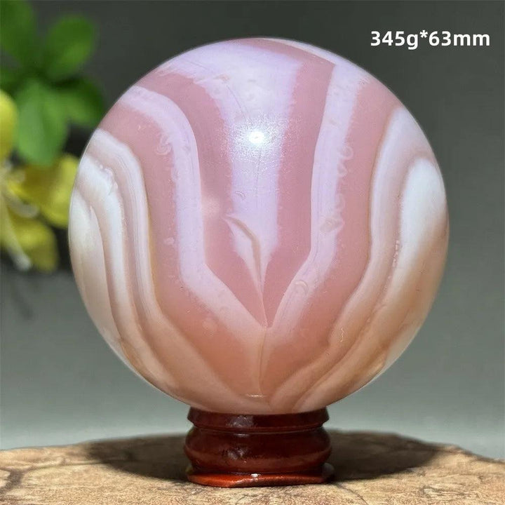 Polished 63mm pink agate crystal sphere featuring soft blush and white concentric banding for heart chakra healing.