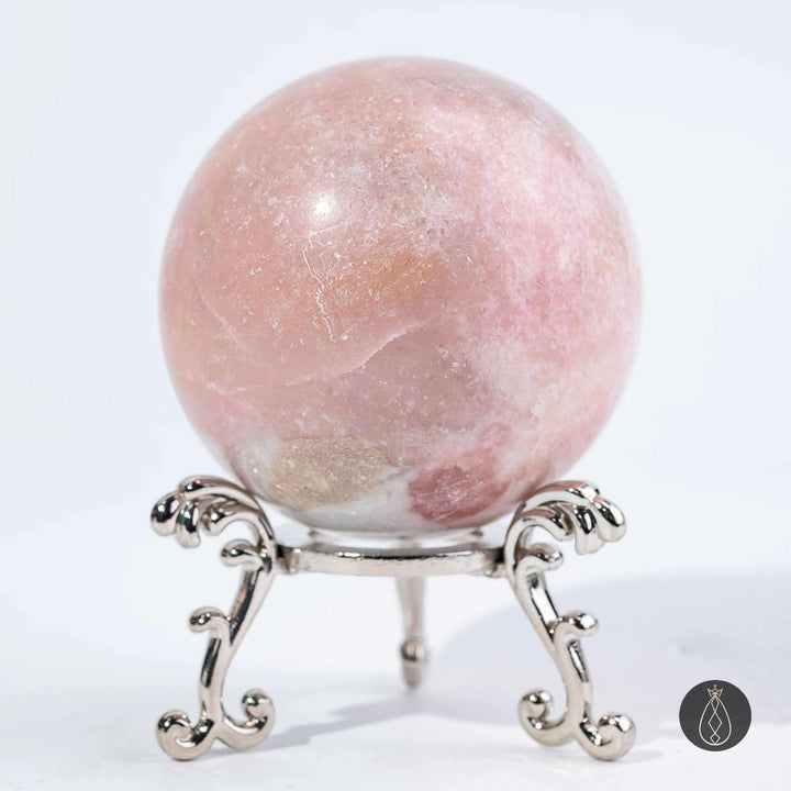 Polished pink opal sphere in blush and bubblegum tones, perfect for heart chakra healing and calm, displayed on a stand.