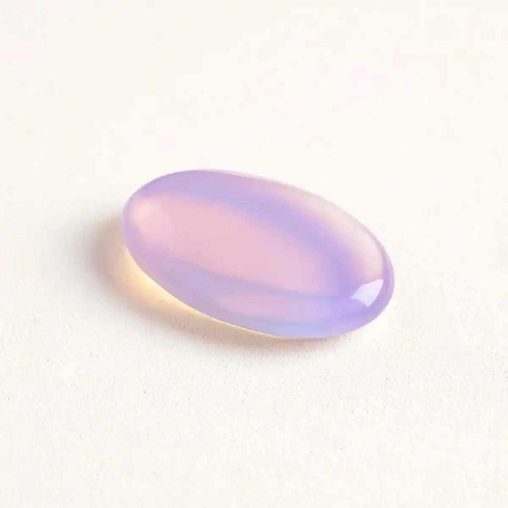 Smooth, milky pink opalite palm stone with a glassy, glowing finish for Heart chakra healing and calm meditation.