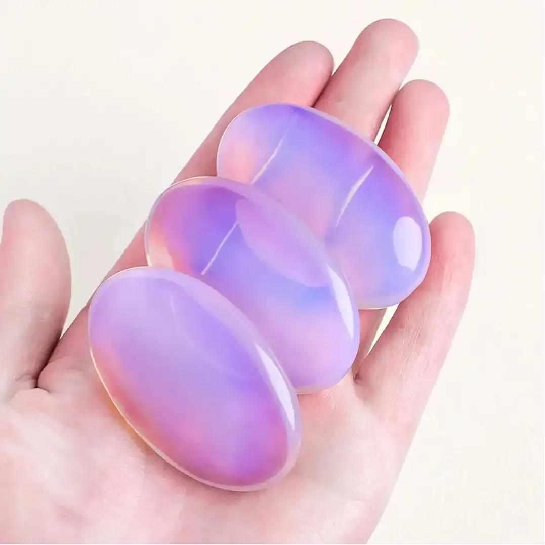Smooth, milky pink opalite palm stone with a glassy, iridescent glow held in a hand for heart chakra meditation.
